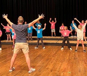 Take It From The Top: Group of people rehearsing a choreographed routine on a stage.